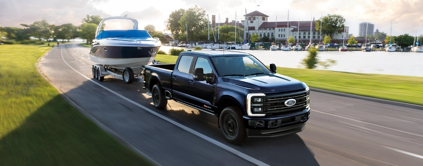 Black 2025 Ford F-350 Platinum towing a boat past a marina